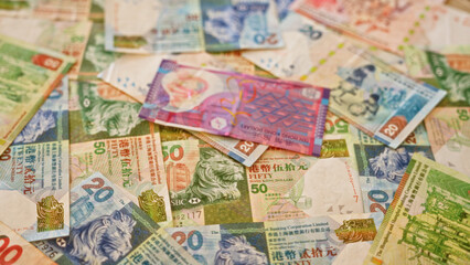 Obraz premium Hong kong dollar bills scattered on a surface showcasing vibrant colors and intricate designs, emphasizing the currency of hong kong in a detailed and rich visual display.