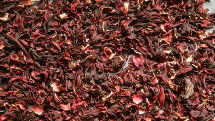 Vibrant dried petals creating a textured background of rich red hibiscus tea leaves spreading across the image © Krakenimages.com