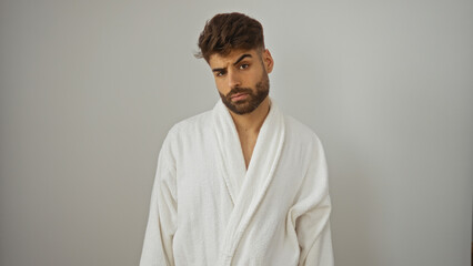 Fototapeta premium Young hispanic man with a beard wearing a white robe over an isolated white background