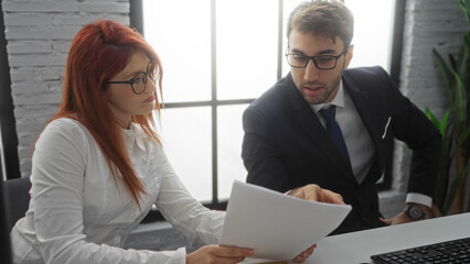 Business partners man woman discussing work at office table interior executives examining documents...
