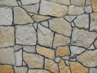 abstraction from facing stone of brown shades with black joints, decoration of exterior of wall or fence using solid natural stone, graphic resource from large abstract shaped stones