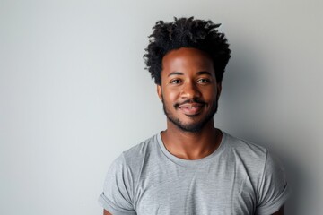 Obraz premium Portrait of a satisfied afro-american man in his 20s dressed in a casual t-shirt in front of plain white digital canvas