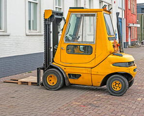 yellow forklift truck is parked outside on the street