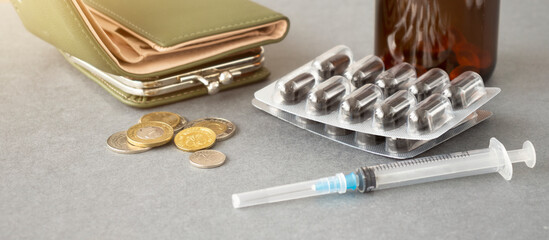 medical costs: crooked stack of different coins and pills on a wooden table, short focus, wallet in...