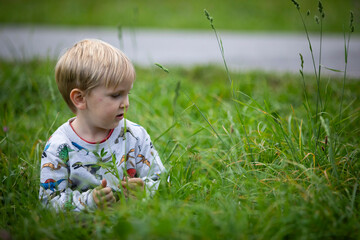 beautiful blond child playing on the ground appreciating nature
