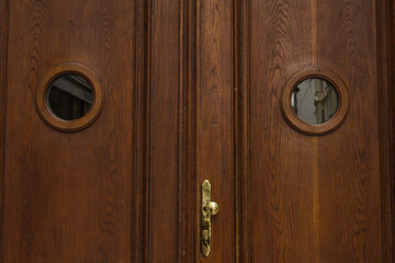 Vienna, Austria - May 12, 2019: Wooden doors front view. Vintage wooden large double barn door with brown wood texture and metallic handle, closeup photo.
