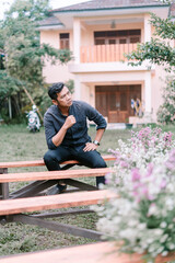 Fototapeta premium A Southeast Asian man sitting on a guest chair at a wedding reception,