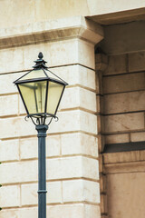 Vienna, Austria - May 12, 2019: Street lampstand. Glowing lantern. A lampstand in front of sandy color stones of residential building. Decorations of streets in Middles ages.