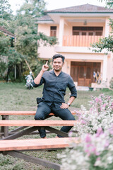 Obraz premium A Southeast Asian man sitting on a guest chair at a wedding reception,