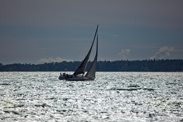 Sailboat silhouette on glistening sea in summer.