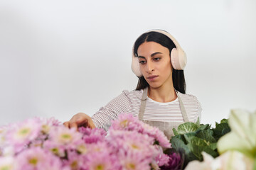 A dedicated florist meticulously arranges colorful blooms while enjoying her craft in the shop.