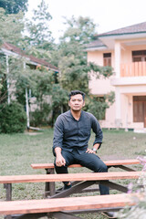 Obraz premium A Southeast Asian man sitting on a guest chair at a wedding reception,