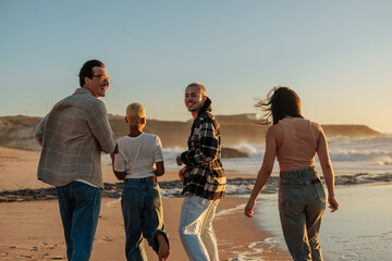 Friends walking on the beach at sunset, enjoying summer vacation
