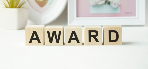 The text of the award on wooden cubes, in the background of the cups