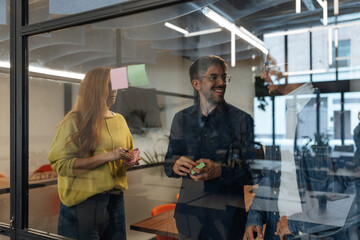 Coworkers brainstorming and sharing ideas using sticky notes in modern office