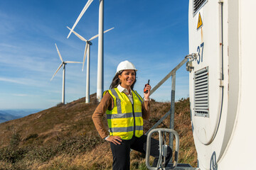 latin Female engineer working at wind turbine power plant holding walkie-talkie