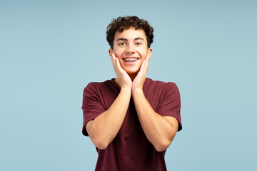 Portrait of happy excited teen boy with braces touching face, looking at camera. Dental care concept