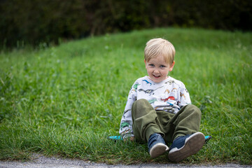 beautiful little and friendly blond boy playing on his skateboard