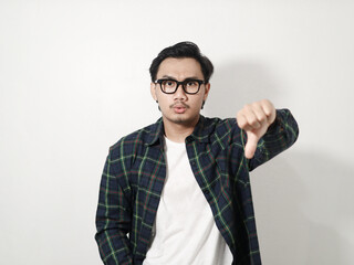 Angry young Asian businessman showing thumbs down gesture isolated on yellow background