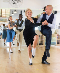 Senior woman and younger man dancing swing in studio
