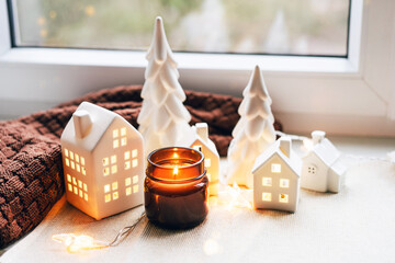 Cozy Christmas Scene with Ceramic Houses and Candlelight by a Window