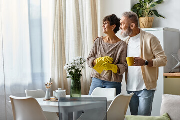 A happy couple stands together in their cozy kitchen, sharing a joyful moment with tea.