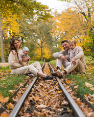 A young family with two children on a walk in an autumn park. Mom holds a little boy in her arms,...