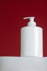 Festive beauty product and a minimalist white pump bottle on red background. Valentine's day. Perfect for holiday skincare, Christmas advertising, or luxury beauty. Winter-themed promotion. Gift.