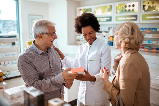 Pharmacist assisting senior couple with medication choice in pharmacy