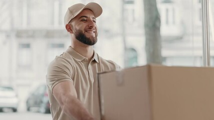 A bearded courier in a cap smiles while handing over a large package to a client, representing prompt and friendly delivery service.