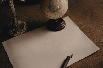 Old calligraphy ink pen are on the old-fashioned table. Ink pen and blank sheet on antique wooden...