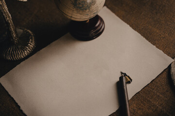 Ink pen and blank sheet on antique wooden desk. An empty white page with an old calligraphy ink pen...