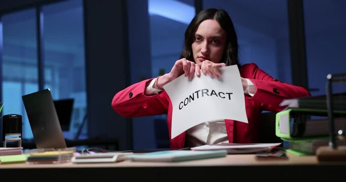 Woman tears sheet of paper with word CONTRACT into small pieces. Businesswoman tears document to convey dissatisfaction with agreement. Slow motion