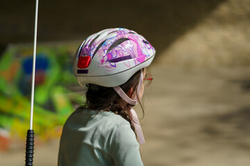 Little cute sad girl cyclist wearing glasses and a helmet. Concept of sad active child