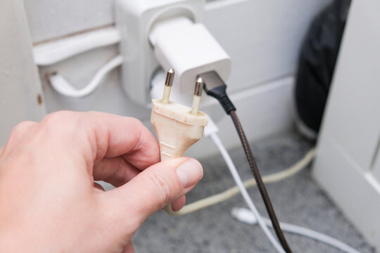 Hand need to plug a socket into a overloaded outlet with an extension and many sockets plugged in, risk of fire and short circuit in a wooden house.