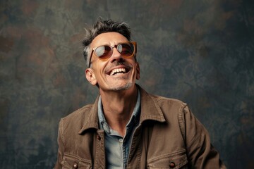 Obraz premium Portrait of a grinning man in his 40s wearing a trendy sunglasses isolated on plain cyclorama studio wall