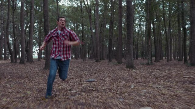 Fearful man running away from something in dark forest
