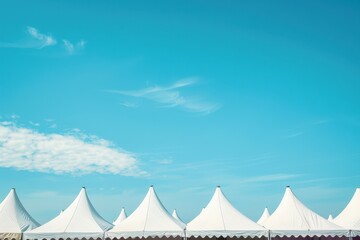 White tents in a row against blue sky
