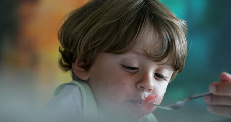 Messy little baby toddler eating, mother giving food for son to eat