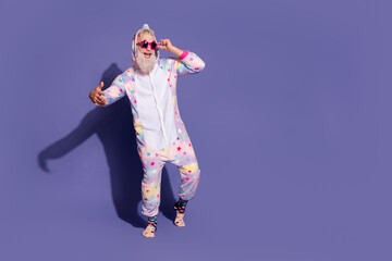 Cheerful man in unicorn pajama posing against purple background for a fun and energizing morning...