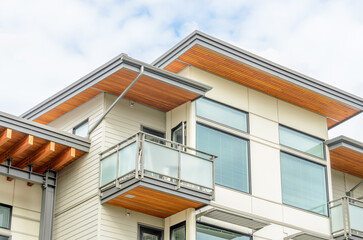 Obraz premium Top of grey luxury house with shingle roof, red and yellow trees and nice windows in Summer in Vancouver, Canada, North America. Day time on June 2024.