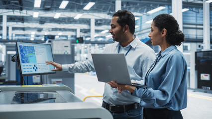 Indian Male Industrial Engineer And Hispanic Female Supervisor Using Laptop And Talking At...