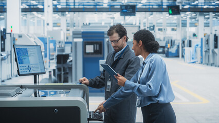Caucasian Male Chief Engineer And Hispanic Female Supervisor Using Tablet And Talking At...