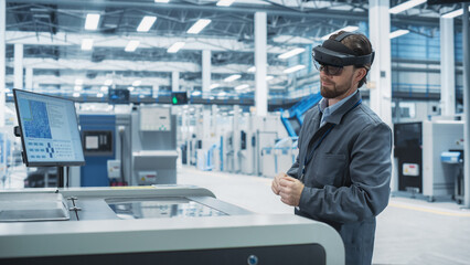 Caucasian Male Engineer Wearing an Augmented Reality Headset And Controlling a Soldering Jet Printer At an Electronics Factory. Technician Using Gestures To Configure Industrial Machinery.