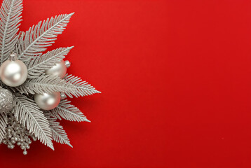 minimalist christmas composition featuring silver ornaments, frosted pine branches, and a vibrant red background. ideal for xmas, new year, holiday cards, festive invitations, and seasonal backdrops.