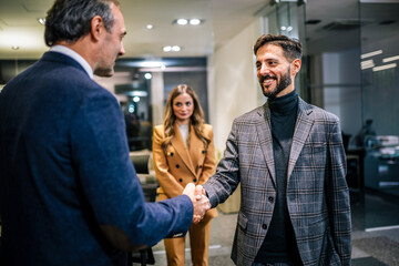 Group of businesspeople standing and shaking hands in a modern office