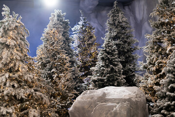 Snow-covered Christmas trees illuminated with warm fairy lights in a magical winter forest setting...