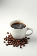 Obraz premium A steaming cup of rich coffee sits on a plain white surface surrounded by several whole coffee beans._00002_