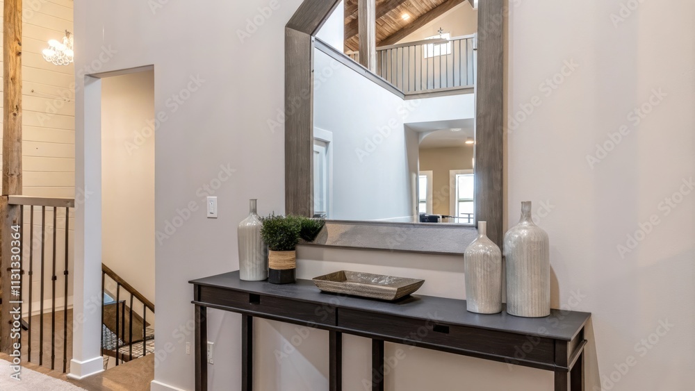 Poster An entryway featuring a sleek console table made of reclaimed wood styled with a few curated decor items and a mirror that reflects the lofts open layout. The walls are kept