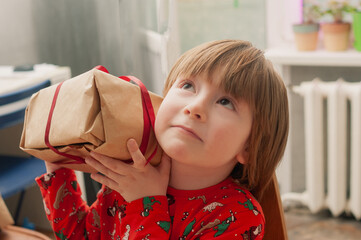 Caucasian boy in red pijamas crafing decorations or opening presents  at home candid shot